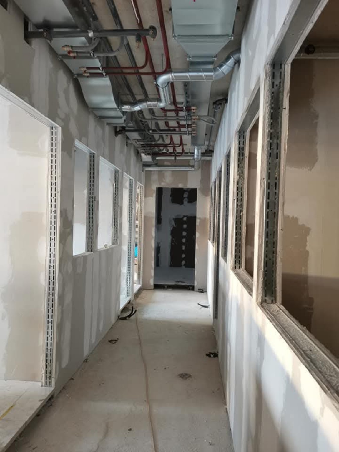 Couloir avec cloisons en plaques de plâtre et installations techniques apparentes au plafond