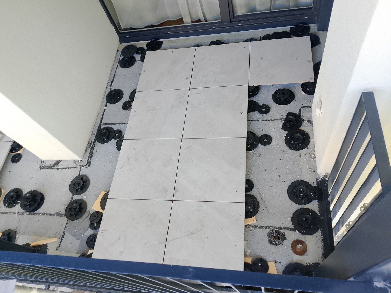 Terrasse en préparation avec plots réglables et premières dalles céramique posées